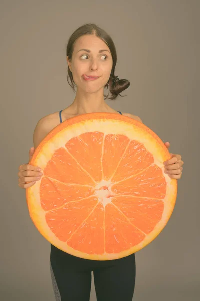 Young beautiful woman ready for gym against gray background — Stock Photo, Image