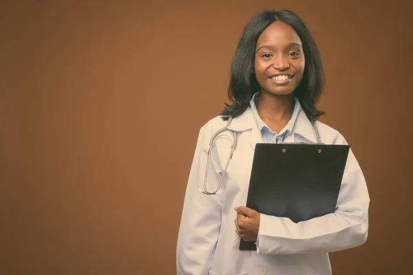 Junge schöne afrikanische Zulu-Ärztin vor braunem Hintergrund — Stockfoto