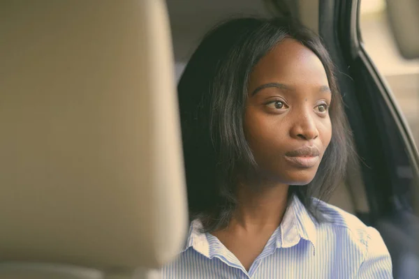Young beautiful African Zulu businesswoman riding inside the car