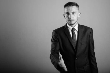 Takım elbiseli genç işadamının siyah beyaz gri arkaplandaki görüntüsü.