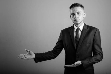 Takım elbiseli genç işadamının siyah beyaz gri arkaplandaki görüntüsü.