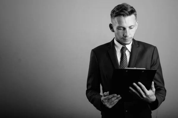 Estudio Joven Empresario Con Traje Sujetando Portapapeles Sobre Fondo Gris —  Fotos de Stock