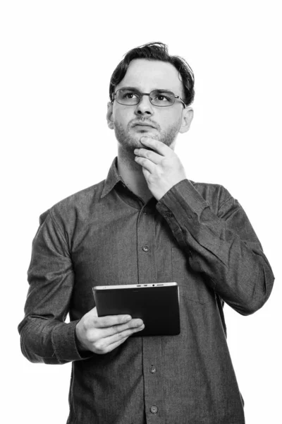 Captura de estudio de un joven formal sosteniendo una tableta digital mientras piensa y mira hacia arriba — Foto de Stock