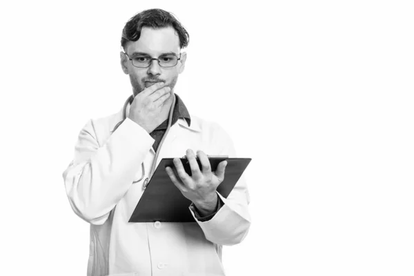 Studio záběr mladého muže lékaře drží schránky při myšlení — Stock fotografie
