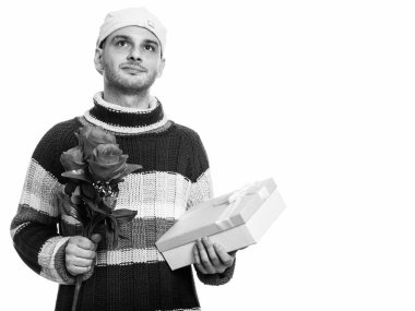 Kırmızı gül ve hediye kutusu düşünürken tutan genç adam stüdyo çekim