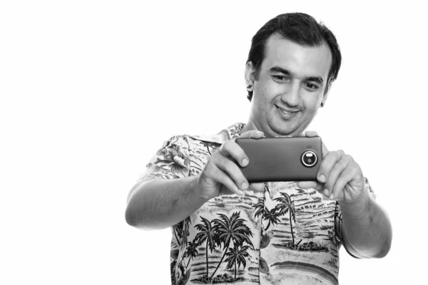 Studio shot di felice uomo persiano sorridente mentre scattava foto con il telefono cellulare — Foto Stock