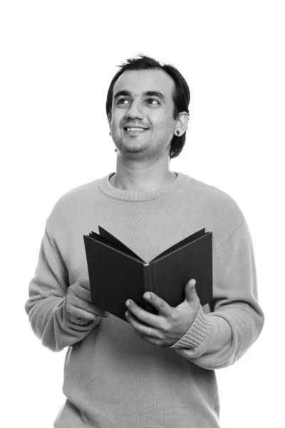 Estúdio tiro de homem persa feliz sorrindo enquanto segurando livro e pensamento — Fotografia de Stock