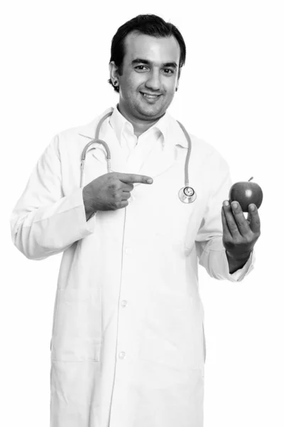 Close up de homem persa feliz médico sorrindo enquanto segurando maçã vermelha e apontando o dedo — Fotografia de Stock