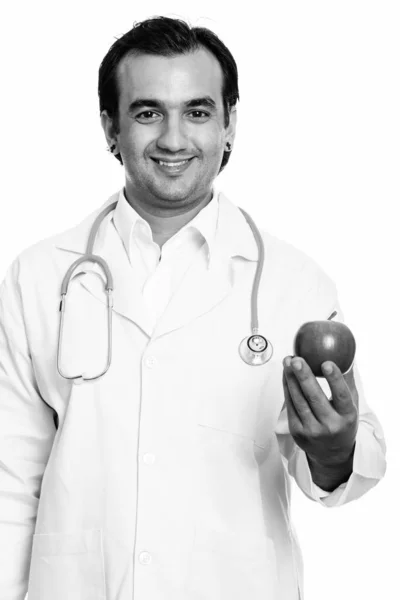 Primer plano de hombre persa feliz médico sonriendo mientras sostiene la manzana roja —  Fotos de Stock