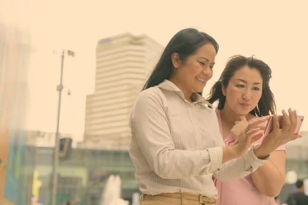 Twee volwassen Aziatische vrouwen samen buiten het winkelcentrum in Bangkok stad — Stockfoto