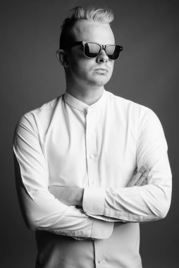 Studio shot of businessman with Mohawk hairstyle and blond hair against gray background in black and white