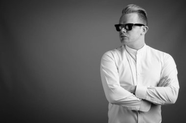 Studio shot of businessman with Mohawk hairstyle and blond hair against gray background in black and white