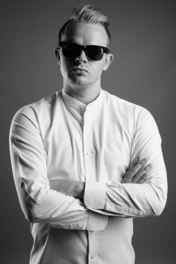 Studio shot of businessman with Mohawk hairstyle and blond hair against gray background in black and white