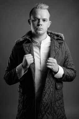 Studio shot of man with Mohawk hairstyle and blond hair against gray background in black and white