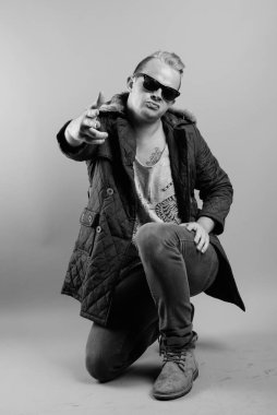Studio shot of man with Mohawk hairstyle and blond hair against gray background in black and white