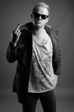 Studio shot of man with Mohawk hairstyle and blond hair against gray background in black and white
