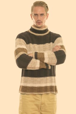 Kollarını kavuşturmuş genç yakışıklı adamın stüdyo fotoğrafı.