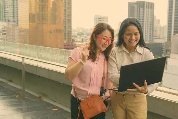 Twee volwassen Aziatische vrouwen samen tegen uitzicht op de stad — Stockfoto