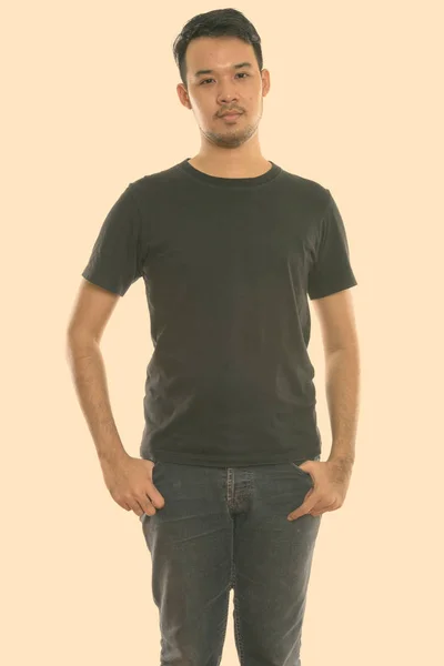 Studio shot of young Asian man standing — Stock Photo, Image