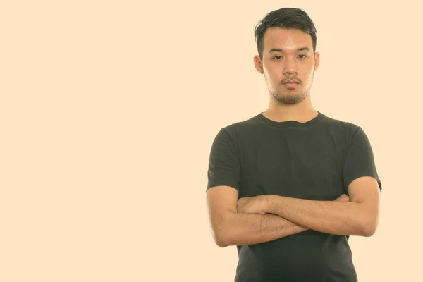 Studio shot van jonge Aziatische man met gekruiste armen — Stockfoto