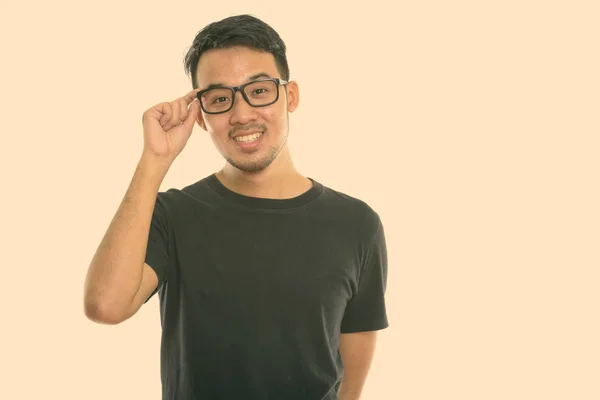 Studio skott av ung glad asiatisk man ler medan du håller glasögon — Stockfoto