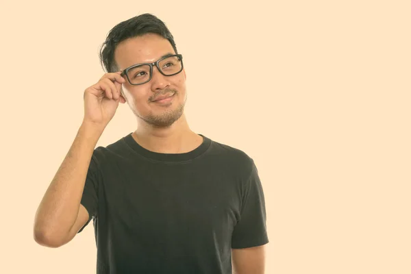 젊은 아시아 남자가 안경을 들고 생각하는 모습을 스튜디오에서 촬영 — 스톡 사진