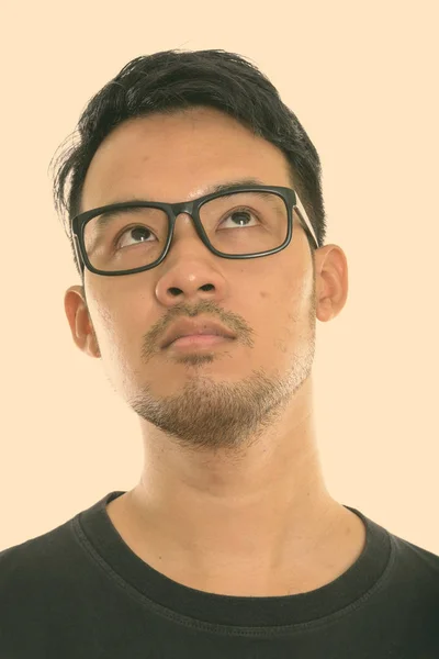 Arc fiatal ázsiai férfi gondolkodás közben felnéz, és visel szemüveget — Stock Fotó