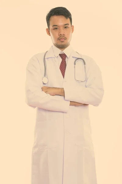 Studio shot de jeune asiatique homme médecin debout avec les bras croisés — Photo