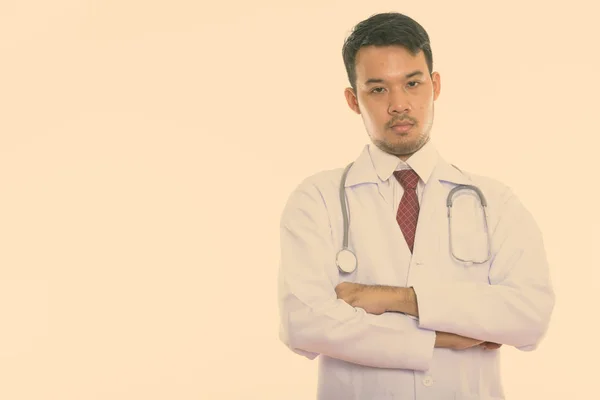 Studio shot de jeune asiatique homme médecin avec les bras croisés — Photo