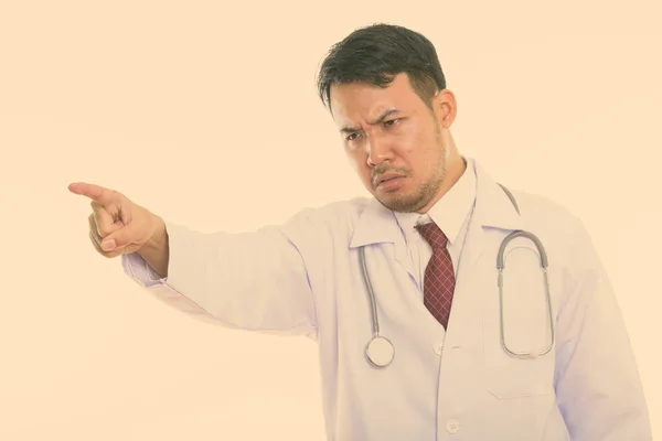 Studio záběr smutný mladík asijské doktor ukazující na dálku — Stock fotografie