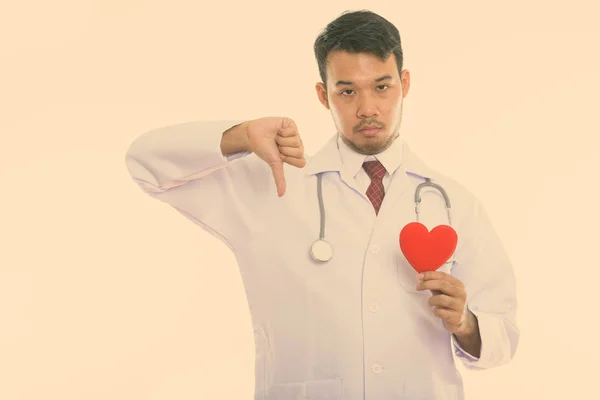 Студийный снимок молодого врача-азиата с красным сердцем и большим пальцем — стоковое фото