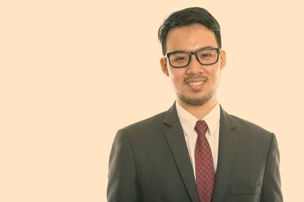 Studio záběr mladý šťastný asijský podnikatel s úsměvem při nošení brýlí — Stock fotografie