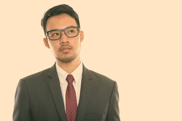 Studio colpo di giovane asiatico businessman indossare occhiali mentre pensare — Foto Stock