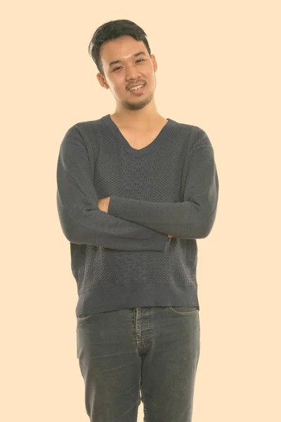 Estudio disparo de joven feliz asiático hombre sonriendo y de pie con los brazos cruzados —  Fotos de Stock