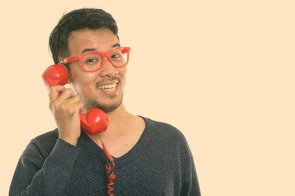 Крупным планом молодой счастливый азиат улыбается во время разговора по старому телефону — стоковое фото