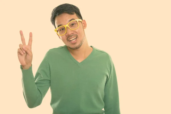 Studio skott av ung glad asiatisk man ler och ger fred tecken — Stockfoto