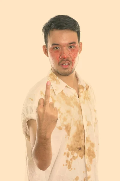 Estúdio tiro de jovem louco asiático homem mostrando seu dedo médio com sangue no rosto — Fotografia de Stock
