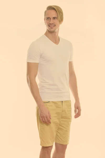 Studio shot of happy young handsome man smiling and standing while thinking — Stock Photo, Image