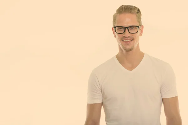 Studio laukaus onnellinen nuori komea mies hymyilee samalla silmälasit — kuvapankkivalokuva