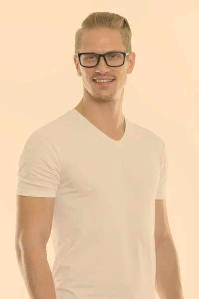 Stúdió lövés boldog fiatal jóképű férfi mosolyog, miközben szemüveget visel — Stock Fotó