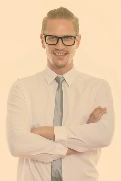 Studio zdjęcie młodego szczęśliwego biznesmena uśmiechniętego i noszącego okulary z skrzyżowanymi ramionami — Zdjęcie stockowe