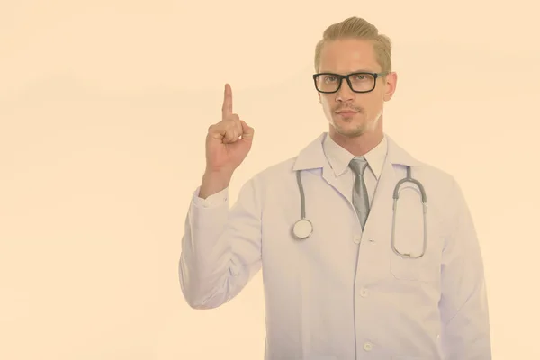 Studioaufnahme eines jungen gutaussehenden Mannes Arzt zeigt mit dem Finger nach oben — Stockfoto