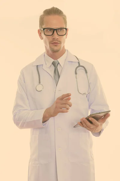 Jovem homem bonito médico segurando tablet digital enquanto pensa e apontando o dedo — Fotografia de Stock