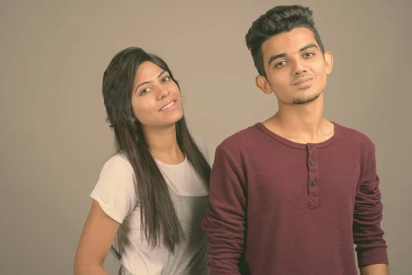 Young Indian man and young Indian woman together against gray background