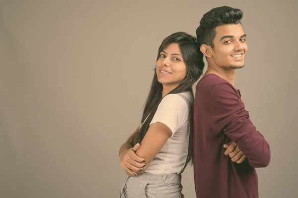 Young Indian man and young Indian woman together against gray background