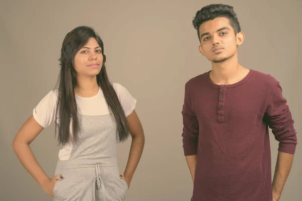 Young Indian man and young Indian woman together against gray background