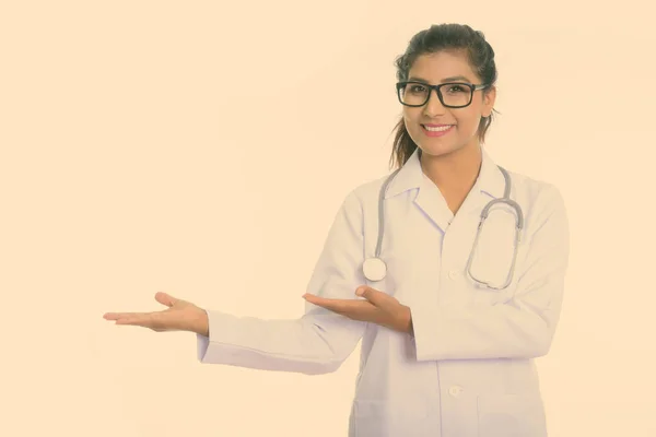 Estúdio tiro de jovem feliz mulher persa médico sorrindo ao mostrar algo isolado contra fundo branco — Fotografia de Stock