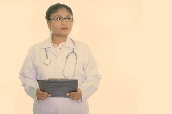 Estúdio tiro de gordura jovem mulher persa médico pensando enquanto segurando prancheta isolada contra fundo branco — Fotografia de Stock