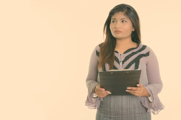 Captura de estudio de la joven mujer de negocios persa gorda pensando mientras sostiene el portapapeles aislado sobre fondo blanco —  Fotos de Stock