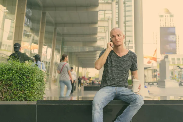 Young handsome bald man using phone in the city outdoors — Stock Photo, Image